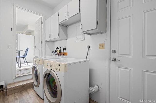 laundry room featuring washer and dryer, light hardwood / wood-style floors, and cabinets