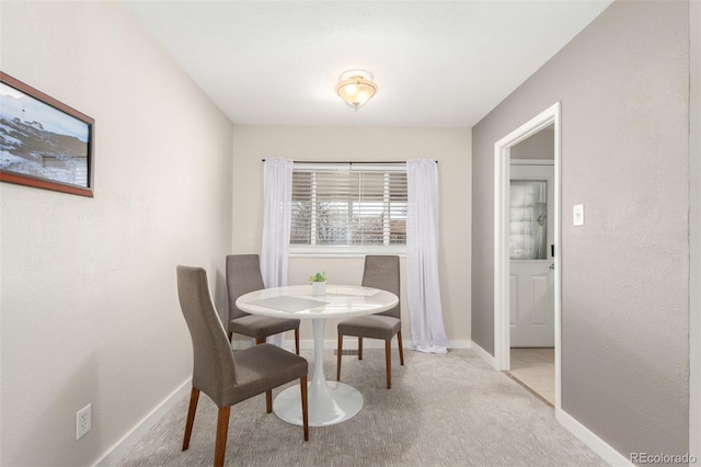 dining area with baseboards and light carpet