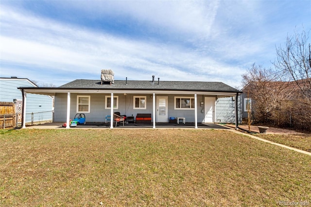 rear view of house with a lawn, a patio, a shingled roof, and fence