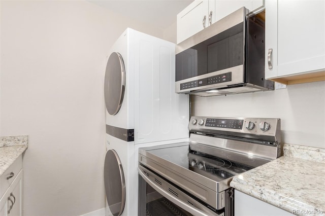 3041 S Glencoe St, Denver, CO 80222 - kitchen featuring stainless steel appliances, stacked washer and clothes dryer, white cabinetry, and light stone countertops
