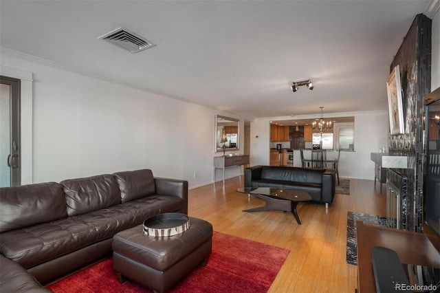 living room with sink, ornamental molding, a chandelier, and hardwood / wood-style flooring