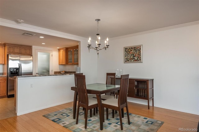 dining area with light wood-type flooring, an inviting chandelier, and crown molding