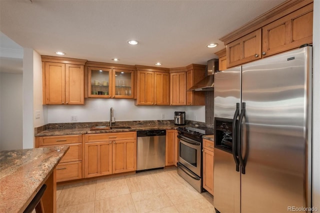 kitchen featuring appliances with stainless steel finishes, wall chimney exhaust hood, dark stone countertops, and sink