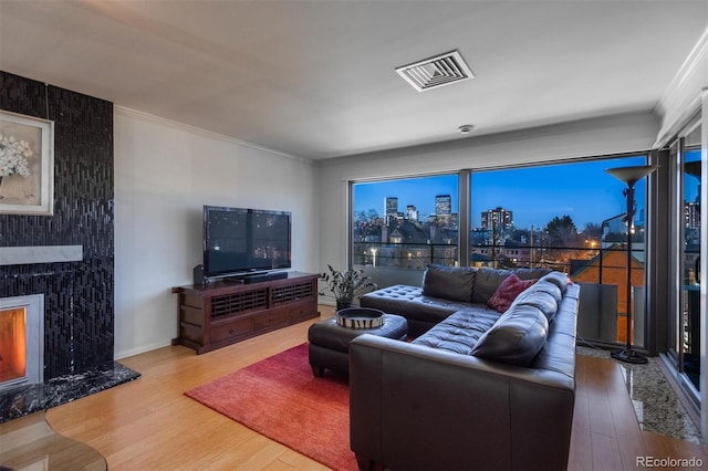 living room featuring hardwood / wood-style floors, crown molding, and a premium fireplace