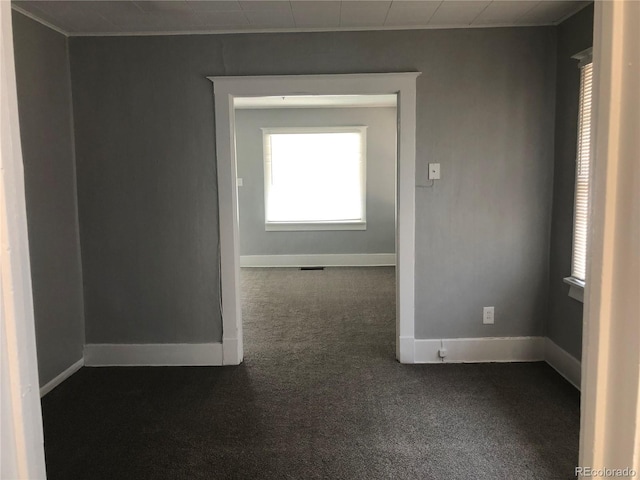 unfurnished room with visible vents, baseboards, and dark carpet