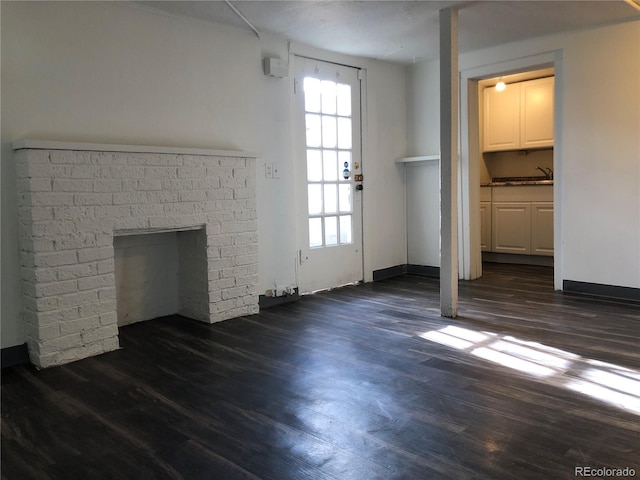 unfurnished living room with dark wood finished floors, a fireplace, and a sink