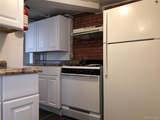 kitchen with under cabinet range hood, white appliances, dark countertops, and white cabinets