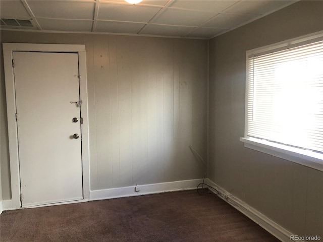 spare room featuring dark colored carpet, visible vents, and baseboards