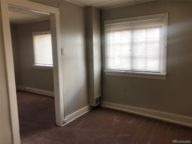 spare room with visible vents, dark colored carpet, and baseboards