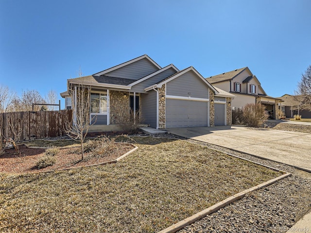 view of front of house featuring an attached garage, stone siding, fence, and concrete driveway