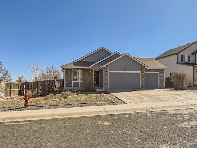 view of front of home featuring stone siding, concrete driveway, an attached garage, and fence