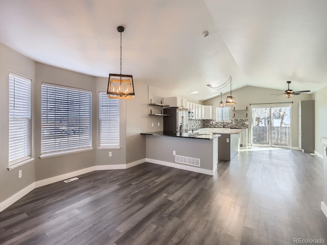 kitchen with lofted ceiling, a peninsula, dark wood-type flooring, visible vents, and open floor plan