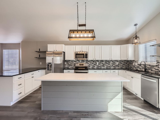 kitchen with a kitchen island, a sink, appliances with stainless steel finishes, decorative backsplash, and dark wood-style floors