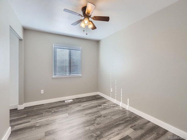 empty room featuring a ceiling fan, baseboards, and wood finished floors