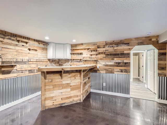 bar with a textured ceiling, wood walls, and recessed lighting