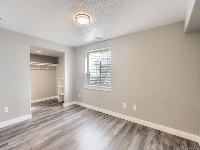 unfurnished bedroom featuring a closet, wood finished floors, visible vents, and baseboards