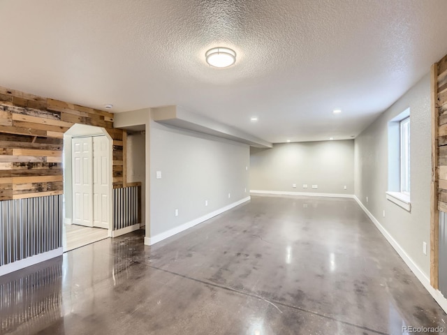 interior space featuring a textured ceiling, wood walls, recessed lighting, and baseboards