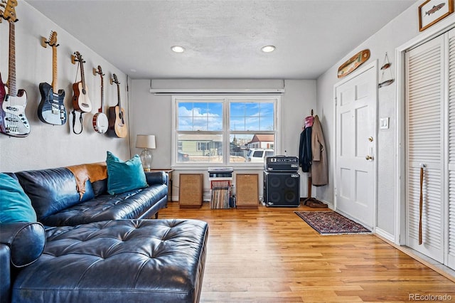 living room featuring recessed lighting, light wood-type flooring, and a textured ceiling