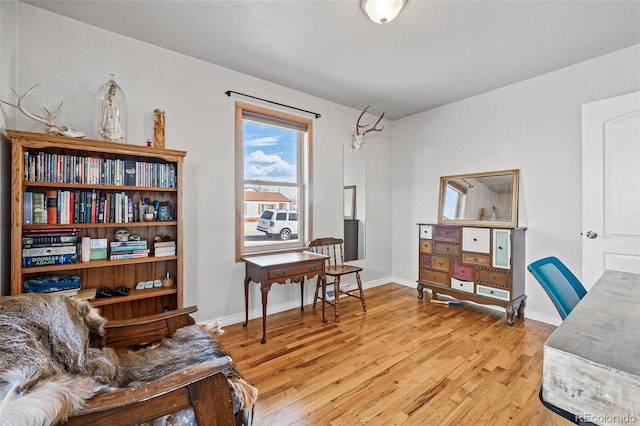 sitting room with baseboards and light wood-type flooring