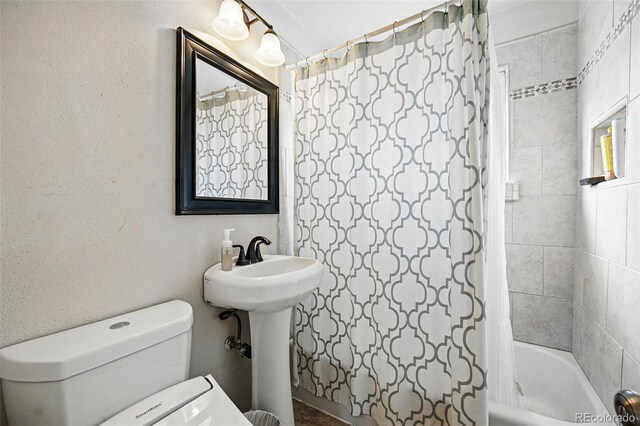 full bathroom with toilet, a sink, and shower / bath combo with shower curtain