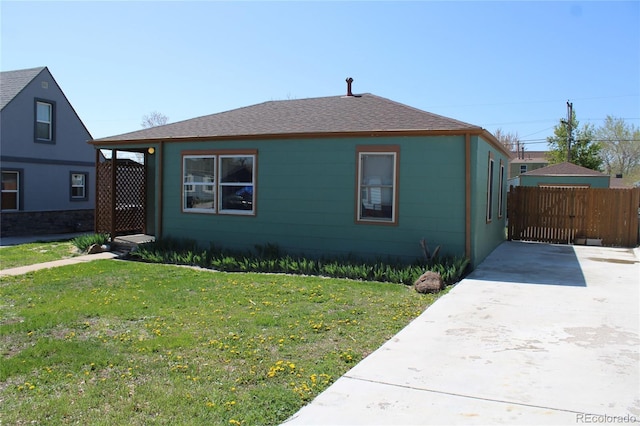 bungalow featuring a shingled roof, a front lawn, and fence