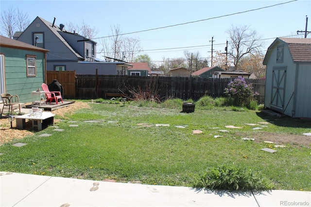 view of yard featuring an outdoor structure, a fenced backyard, and a storage shed