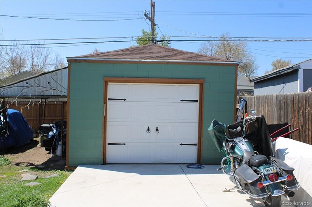 detached garage with concrete driveway and fence