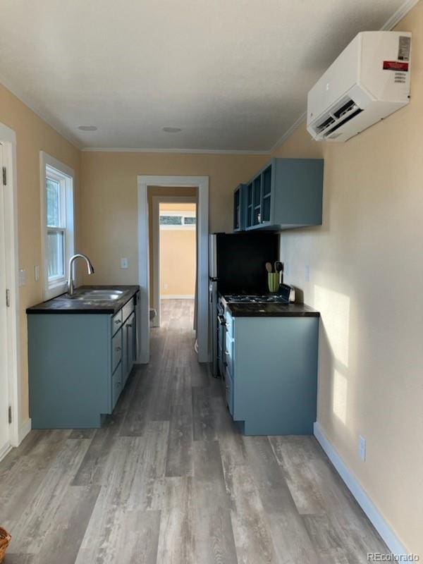 kitchen featuring sink, crown molding, blue cabinetry, hardwood / wood-style floors, and an AC wall unit