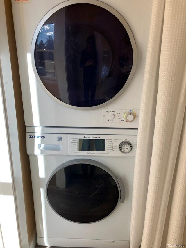 clothes washing area with stacked washer and clothes dryer