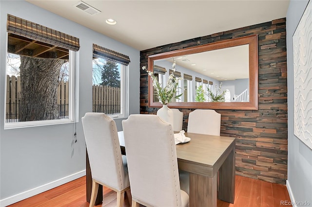 dining space featuring wood-type flooring and wooden walls