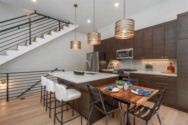 21 Washington Ave, Golden, CO 80403 - kitchen featuring appliances with stainless steel finishes, a kitchen breakfast bar, light wood-style flooring, dark brown cabinets, and recessed lighting