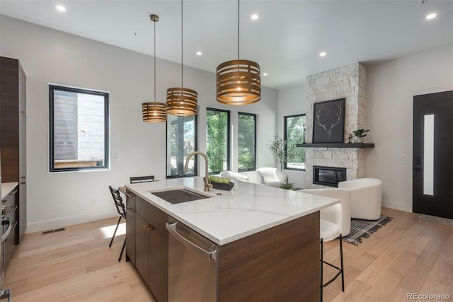 21 Washington Ave, Golden, CO 80403 - kitchen featuring dishwasher, a fireplace, a breakfast bar area, light wood-style floors, and recessed lighting