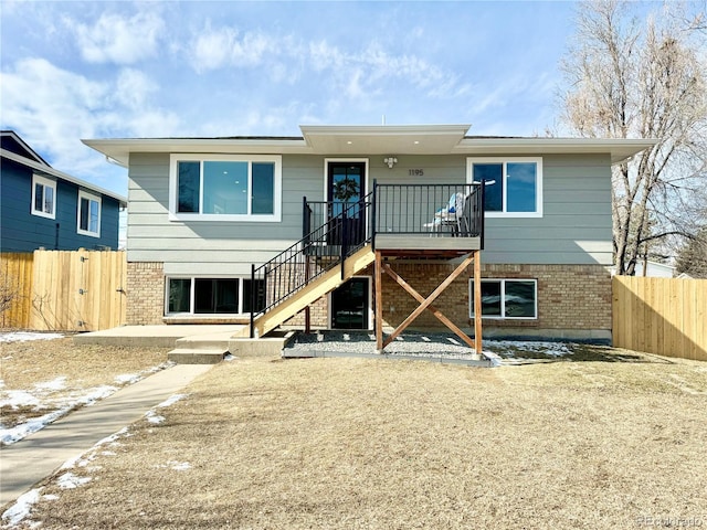 exterior space featuring stairs, fence, and brick siding