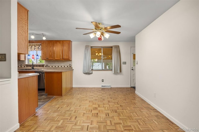 1026 Spencer St, Longmont, CO 80501 - kitchen with brown cabinetry, ceiling fan, light countertops, stainless steel dishwasher, and tasteful backsplash