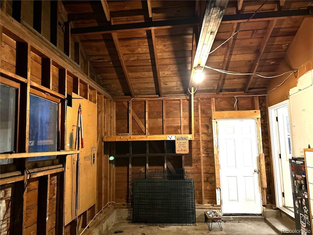 interior space featuring lofted ceiling with beams, wooden ceiling, and wood walls