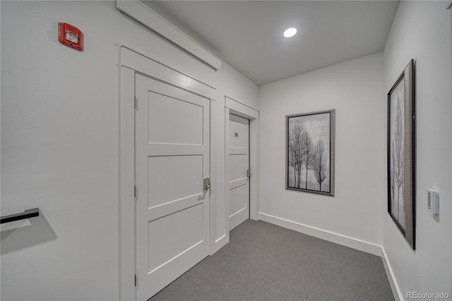 hallway featuring recessed lighting, dark carpet, and baseboards