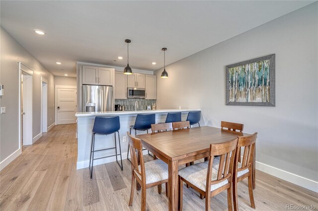 dining space featuring baseboards, recessed lighting, and light wood-style floors