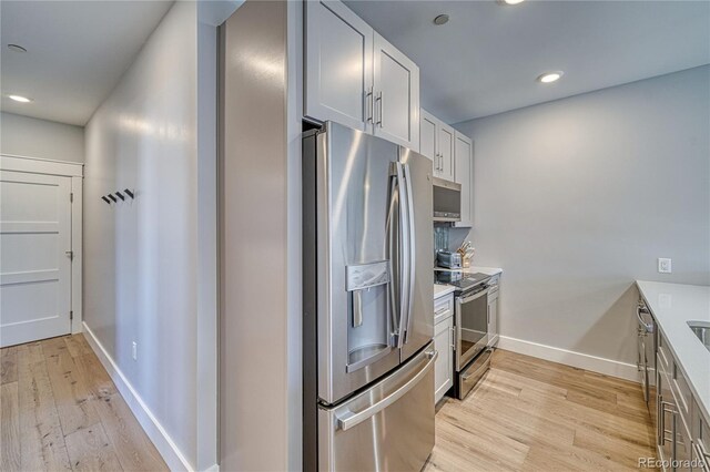 kitchen with light wood finished floors, baseboards, stainless steel appliances, and light countertops