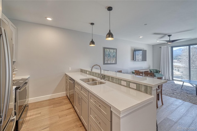 kitchen featuring a peninsula, light wood finished floors, light countertops, and a sink