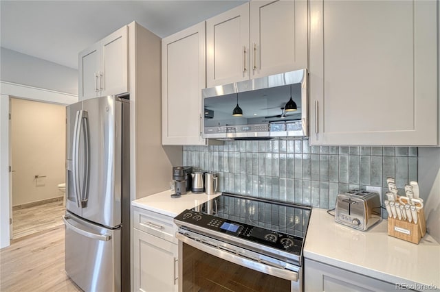 kitchen with stainless steel appliances, light countertops, backsplash, light wood-style flooring, and white cabinetry