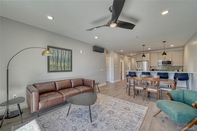 living area featuring light wood-style flooring, baseboards, a ceiling fan, and recessed lighting