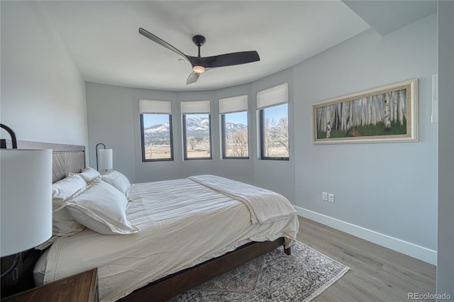 bedroom featuring a ceiling fan, baseboards, and wood finished floors