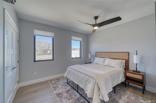 bedroom featuring a ceiling fan, light wood-style flooring, and baseboards