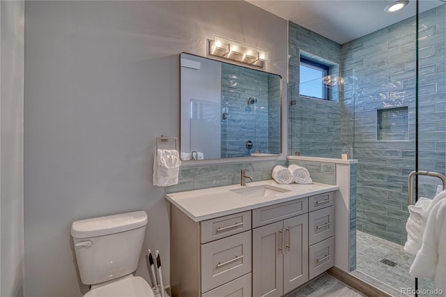 bathroom with backsplash, a tile shower, vanity, and toilet