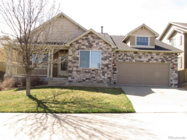 view of front of home featuring a front yard, driveway, stone siding, and a garage