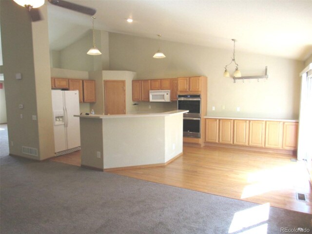 kitchen with visible vents, white appliances, high vaulted ceiling, a center island, and hanging light fixtures