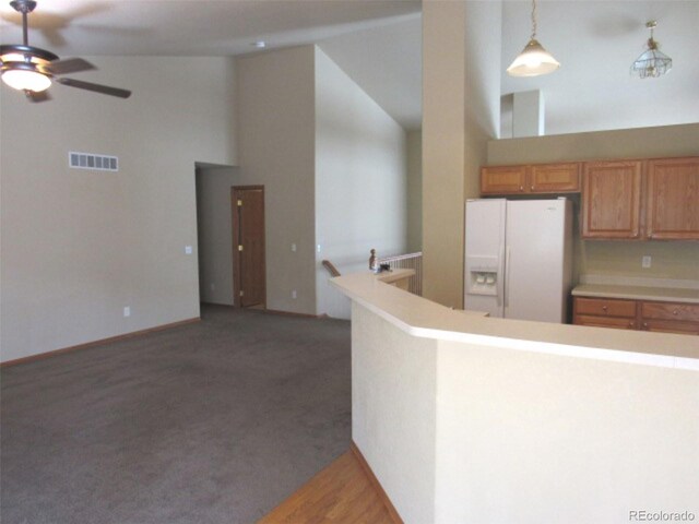 kitchen with a ceiling fan, visible vents, light countertops, high vaulted ceiling, and white fridge with ice dispenser