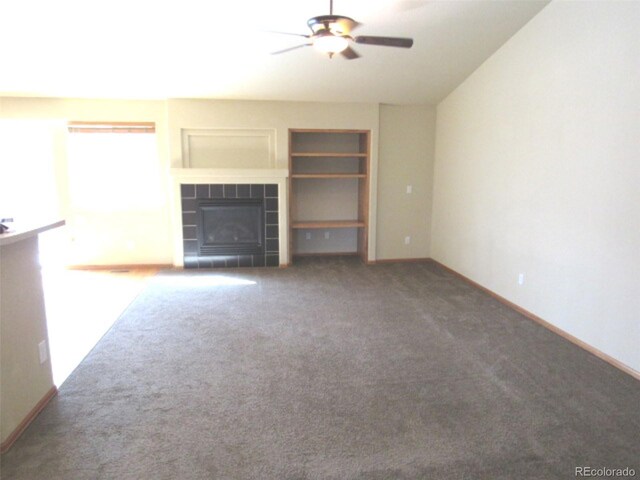 unfurnished living room featuring a fireplace, carpet, a ceiling fan, and built in shelves