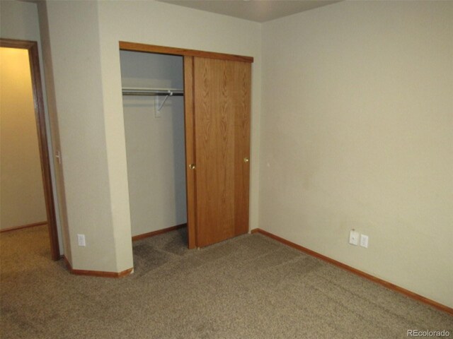 unfurnished bedroom featuring baseboards, carpet, and a closet