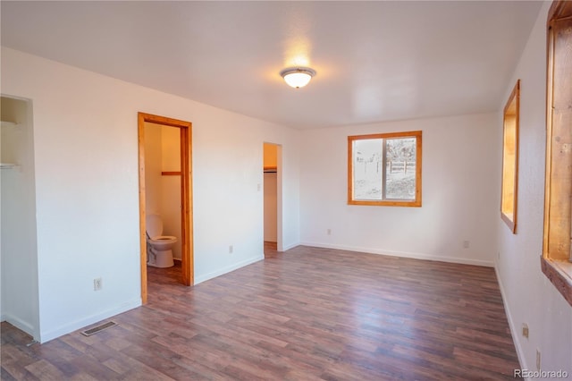 unfurnished bedroom featuring dark hardwood / wood-style floors, a spacious closet, and connected bathroom